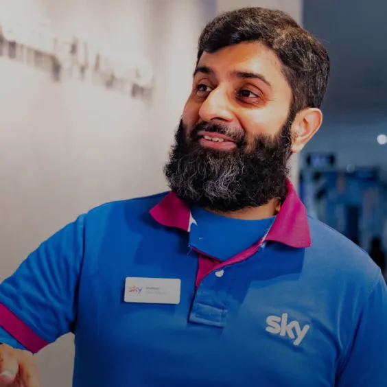 Bearded asian man wearing Sky branded clothing talks to a customer