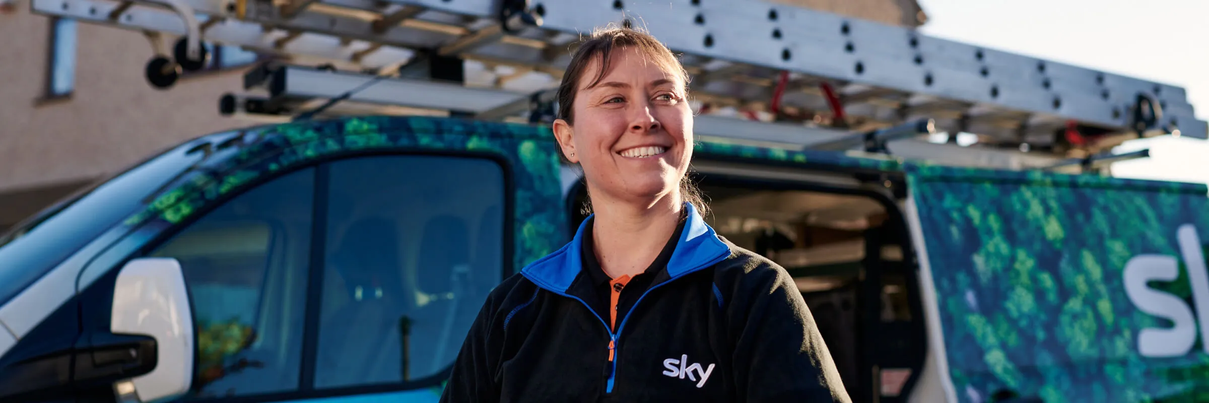 Smiling female engineer stood in front of work van