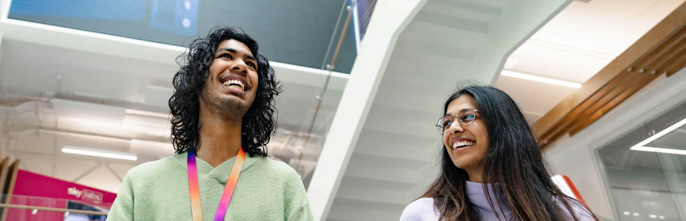 Two smiling colleagues walking through modern office